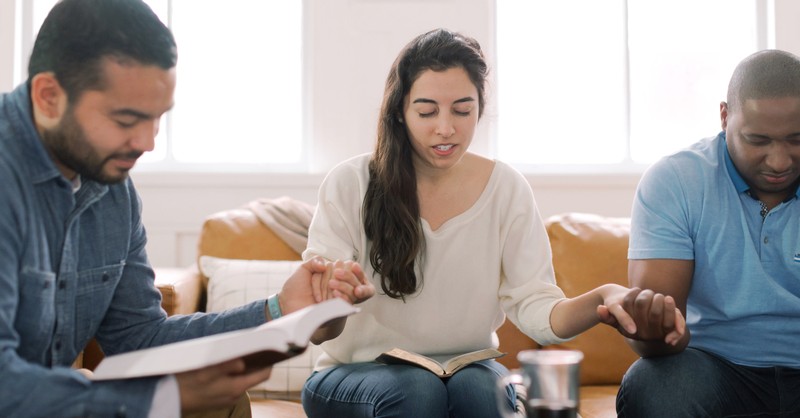 bible study group praying and holding hands together