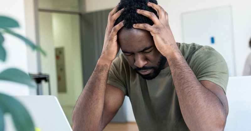 stressed at work man holding head in hands overcome anxiety