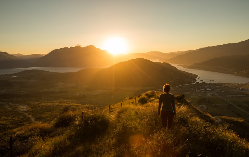 woman standing on hill looking over beautiful valley as the sun rises, how to never miss what god is doing in your life