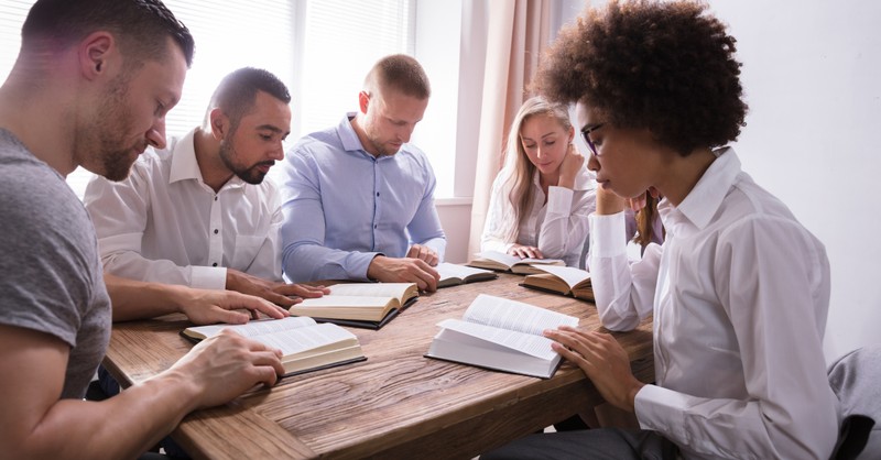 Diverse group of people with Bible's open around a table studying.