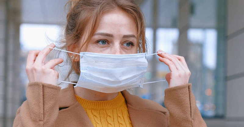 woman putting on face mask