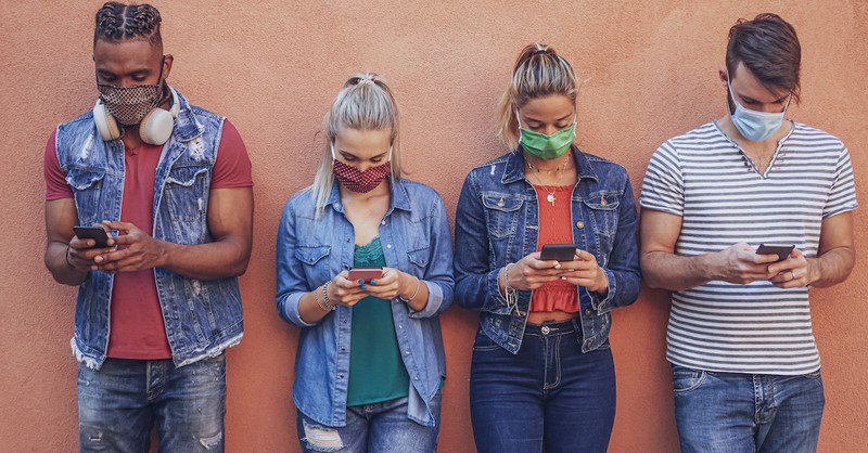 teenagers with masks standing against wall using smart phones, praying armor of god