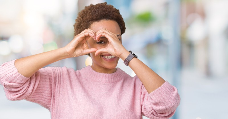 woman making heart with hands over eye to signify apple of my eye