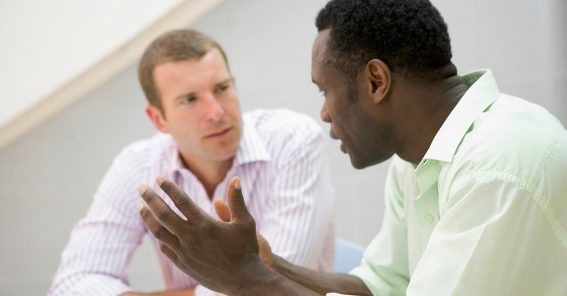 two diverse races men in serious conversation