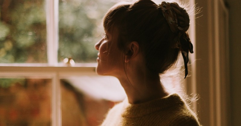 woman in sweater looking out window, day by day hymns about heaven
