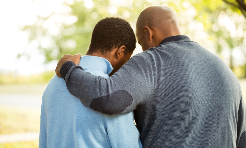 dad with arm around teen son apologizing hugging or praying