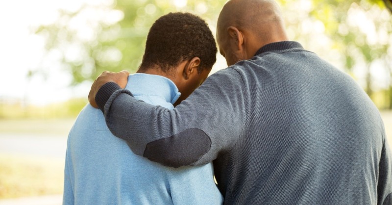 dad with arm around teen son apologizing hugging or praying