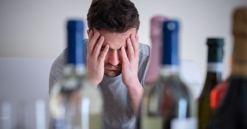 man with head in hands battling alcohol addiction