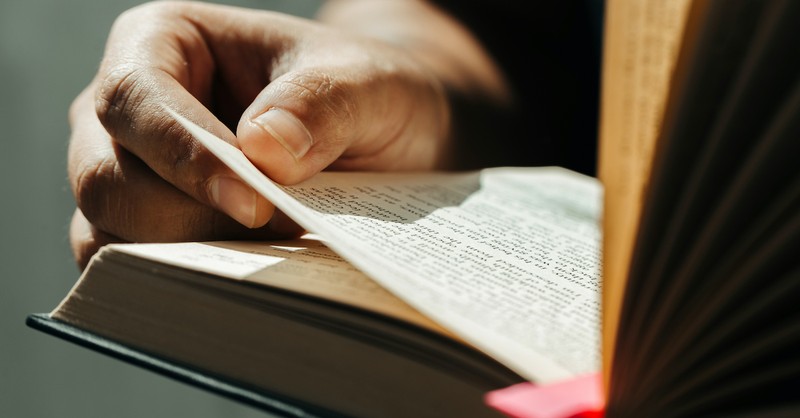 hand holding page reading open Bible