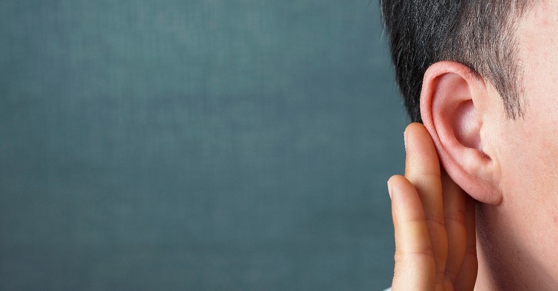 close up of hand held to ear listening