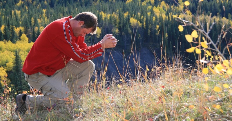 man bowing down in prayer outdoors lead with integrity