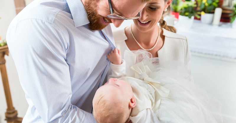 young couple holding baby in church for dedication or baptism, honor your father