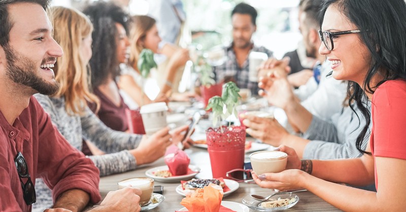 group of friends having brunch together happily at table, eat drink and be merry
