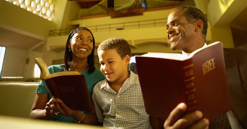 couple reading bible in church with family