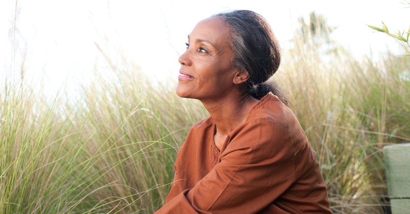 woman sitting in field peacefully looking out into nature