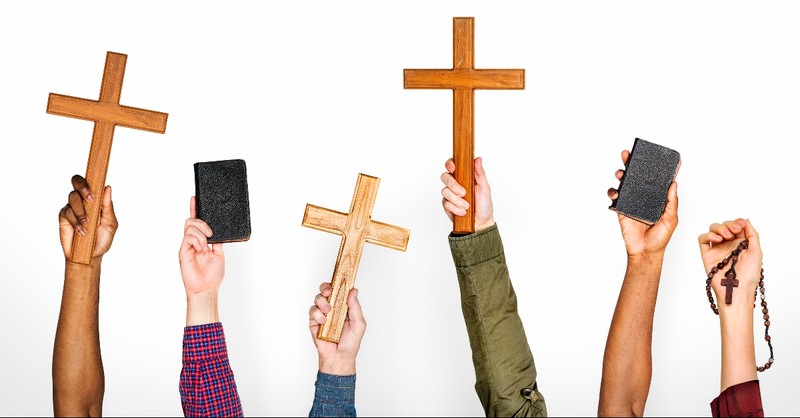 Hands holding up crosses and Bibles