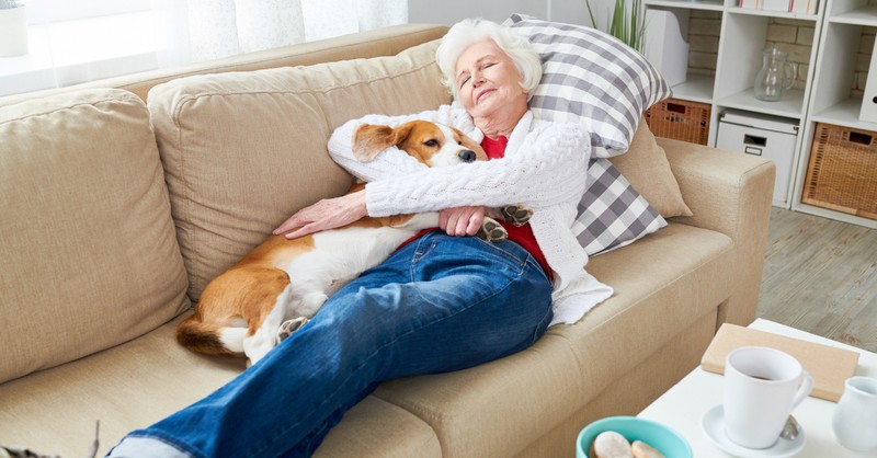 senior mature woman napping on couch with dog to relieve stress