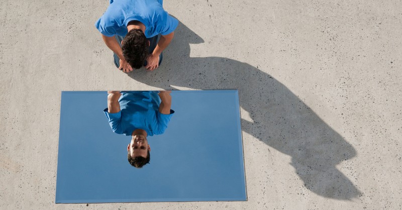 man looking in mirror at reflection on ground