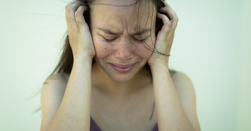 woman holding her head looking scared and distressed, how to pray when thoughts out of control