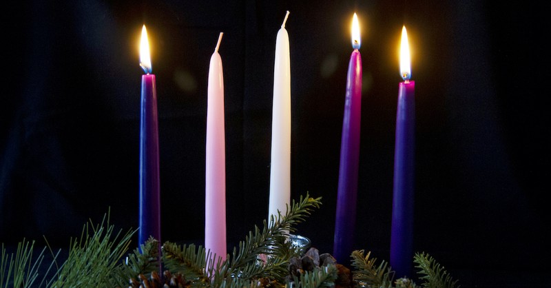 advent wreath and three lit candles with black background