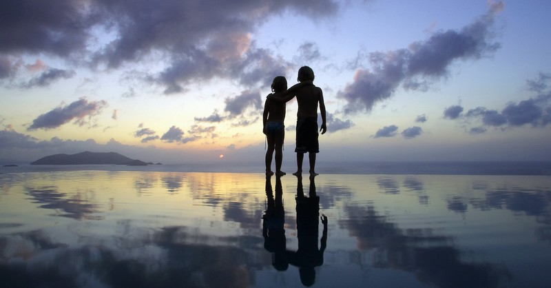 Two children with arms resting on each other's shoulders on the beach at sunset, did Jesus have half-siblings?