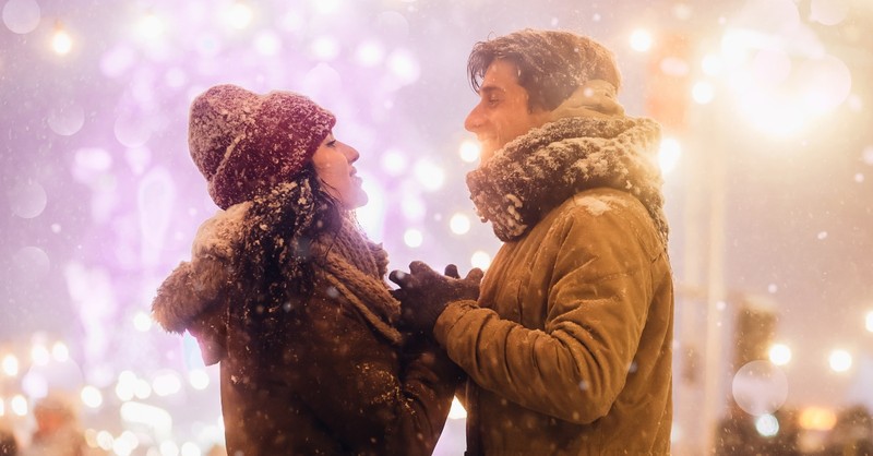 couple having romantic date in snowy christmas setting, falling in love at christmas hallmark