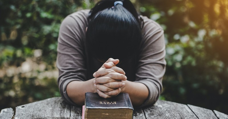 woman praying with hands on holy Bible, how to ask God for forgiveness