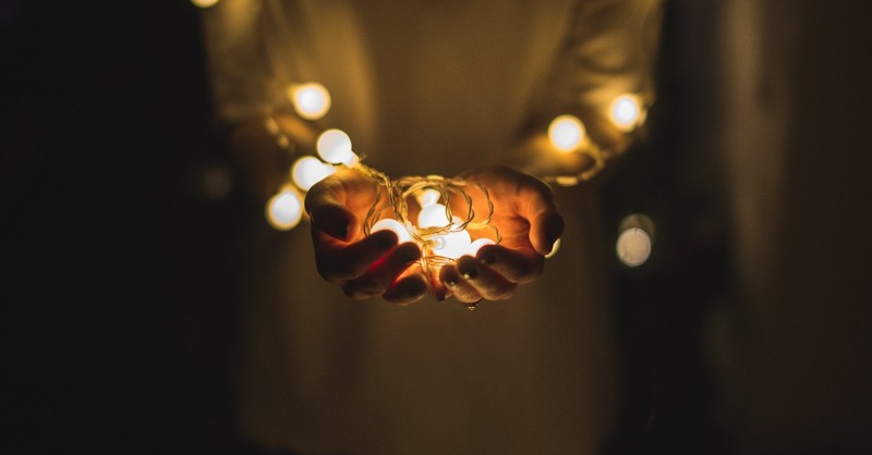 hands holding fairy lights in hands in darkness, top 10 messages of hope in crisis 2020