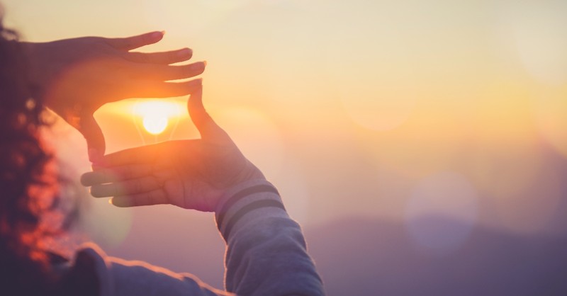 woman holding hands framing sunrise, how to plan spiritual retreat