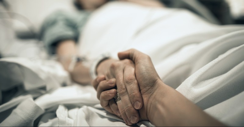 Hand holding on a hospital bed, blessed are the peacemakers