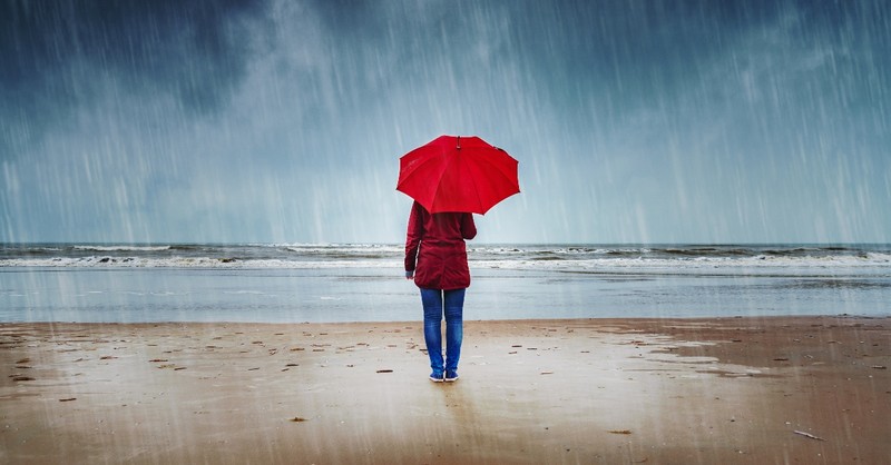 woman standing with umbrella in rain on beach, myths in church about mental health