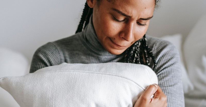 woman hugging pillow crying looking sad and worried, prayers for anxiety life uncertain