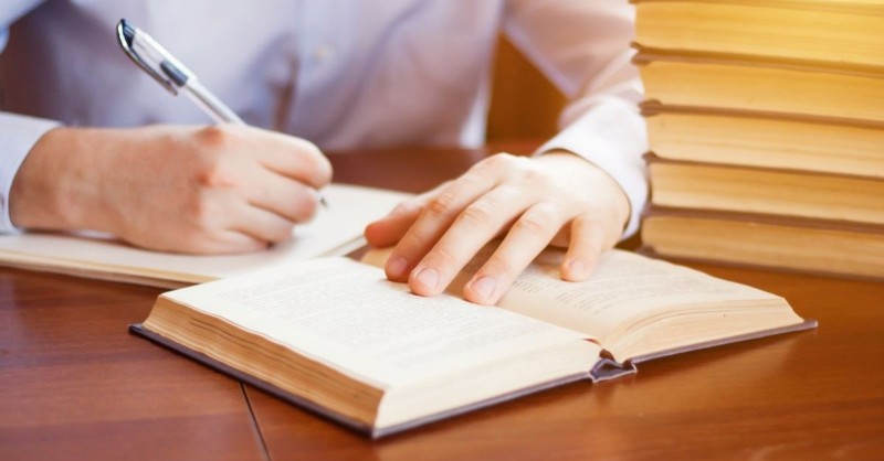 man studying bible at desk with pen and notes