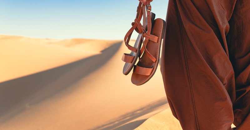 Holding sandals on the beach