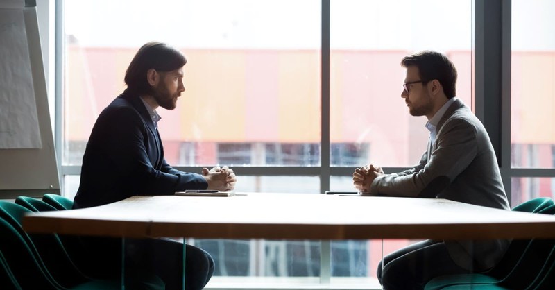 Two men glaring at each other across a table