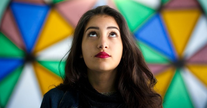 Woman standing in front of stained glass, looking up at the sky, God