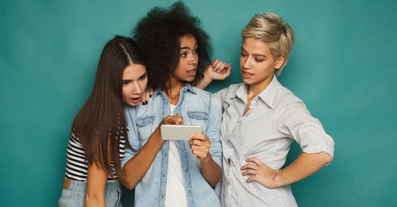 group of women girls looking at phone judgmental cancel culture shocked surprised surprised