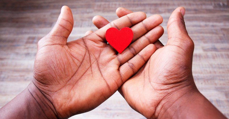 open hands holding paper red heart