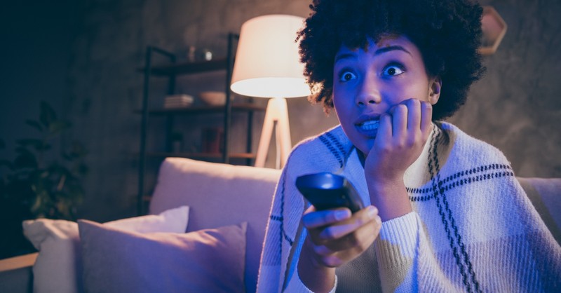 woman watching tv at home alone looking scared, how to live alone