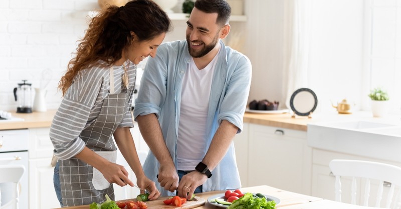man and woman in kitchen cooking laughing and smiling