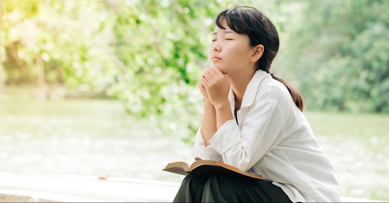 Woman praying with a Bible on her lap