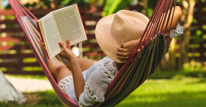 Woman relaxing in a hammock with a book
