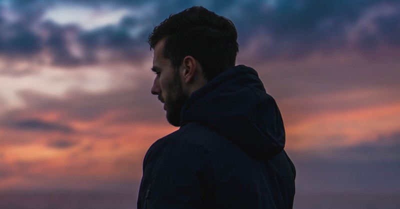 man looking at sunset thoughtfully