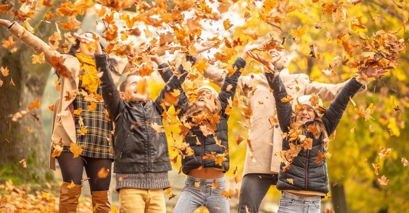 Family all throwing colorful fall leaves in the air