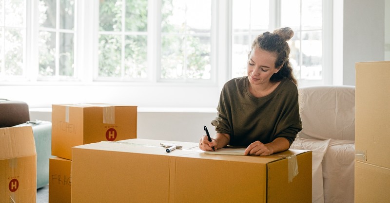 woman writing labels on boxes packing up house