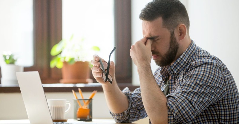 Um homem exausto em frente ao seu laptop