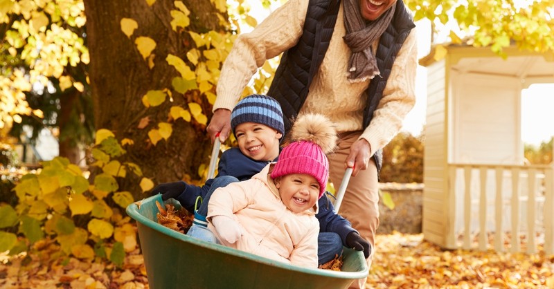 kids riding in wheelbarrow having fun dad pushing them in the fall