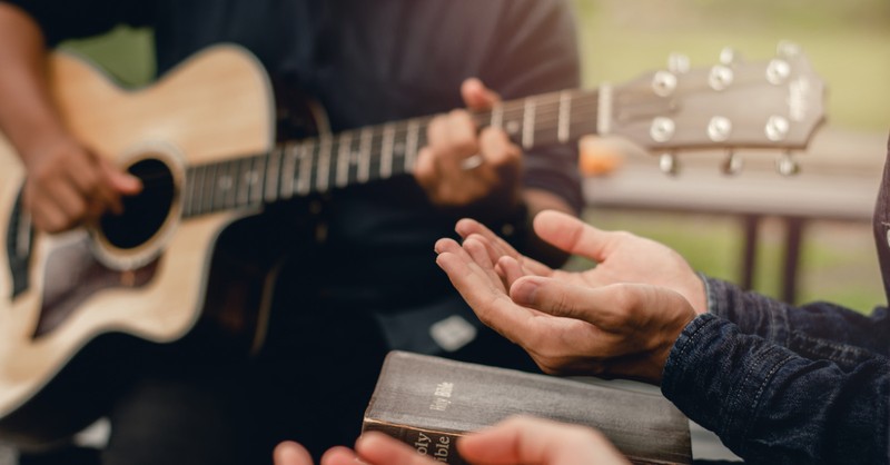 a person playing a guitar and a person holding a Bible, o for a thousand tongues to sing hymns about freedom