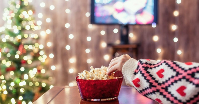 Woman reaching for popcorn watching a Christmas movie