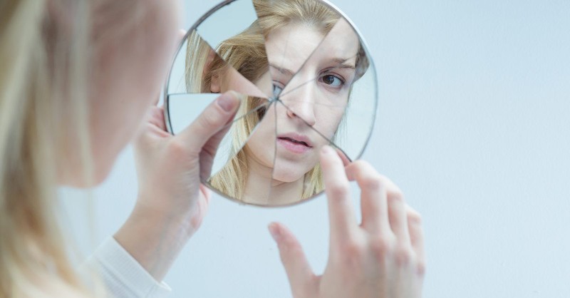Woman looking at herself in a cracked mirror
